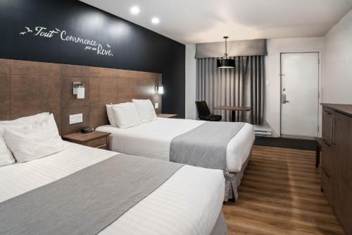 拉图克Hôtel Marineau La Tuque的酒店客房设有两张床和一张桌子。