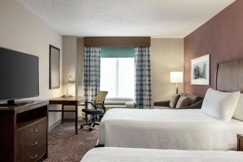 路易斯威尔路易斯维尔市中心希尔顿花园酒店的酒店客房设有两张床、一张桌子和一台电视。