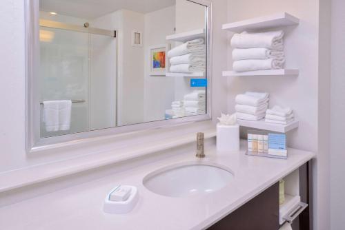 西塔科西雅图机场汉普顿酒店的浴室配有盥洗盆、镜子和毛巾