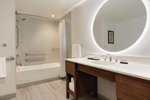 南乔丹南约旦盐湖城希尔顿大使馆套房酒店 的一间带水槽、浴缸和镜子的浴室