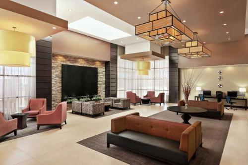 西瓦利城Embassy Suites by Hilton Salt Lake West Valley City的大堂配有沙发、椅子和电视。