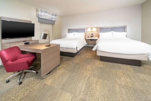 圣玛丽亚Hampton Inn & Suites Santa Maria的酒店客房设有两张床、一张桌子和一台电视。