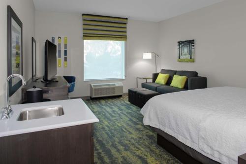 尔湾汉普顿尔湾/橘郡机场酒店的酒店客房设有床、水槽和沙发。