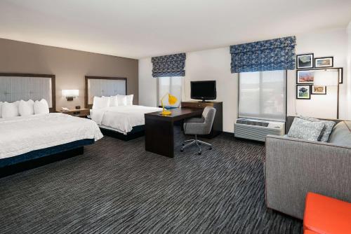 圣马科斯圣马科斯汉普顿套房酒店的酒店客房设有两张床、一张桌子和一张沙发。