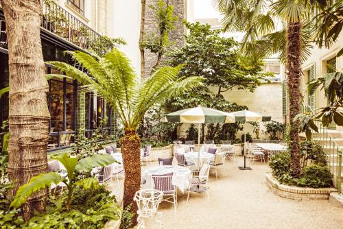 巴黎Hôtel Eldorado Paris的一个带桌椅的庭院,棕榈树