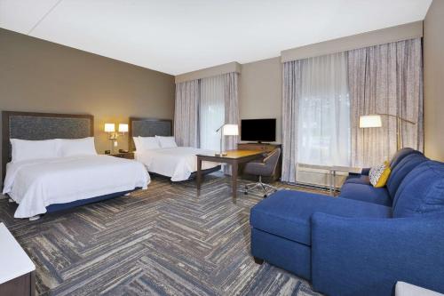 威尔斯井奥甘奎特汉普顿套房酒店 的酒店客房,设有两张床和一张蓝色的沙发