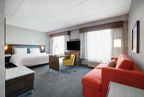 滑铁卢Hampton Inn & Suites By Hilton Waterloo St. Jacobs的酒店客房配有床、沙发和电视。