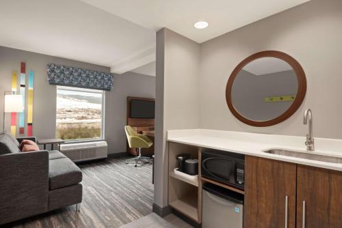 基洛纳Hampton Inn & Suites Kelowna, British Columbia, Canada的酒店客房设有沙发、水槽和镜子