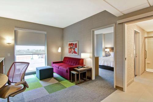 多瓦尔Home2 Suites By Hilton Montreal Dorval的酒店客房配有红色的沙发和床。