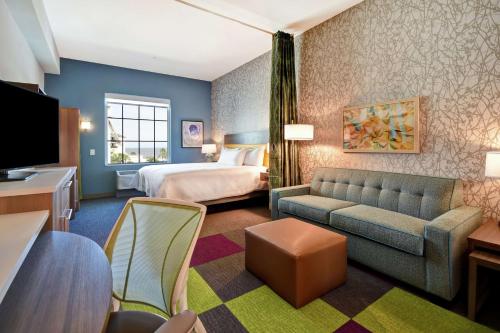 杰基尔岛Home2 Suites By Hilton Jekyll Island的酒店客房,配有床和沙发