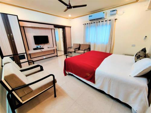 卡兰古特Shradha luxury room的一间卧室配有一张床、一把椅子和电视