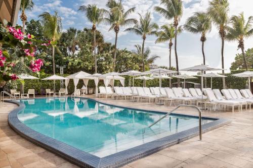 迈阿密海滩Hilton Bentley Miami South Beach的度假村的游泳池配有椅子和遮阳伞