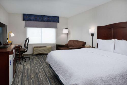 海伦娜海伦娜汉普顿酒店的酒店客房设有一张大床和一张书桌。