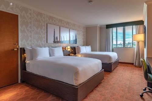 圣地亚哥圣地亚哥市中心希尔顿逸林酒店的酒店客房设有两张床和窗户。