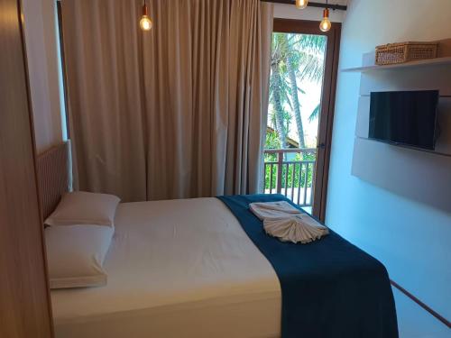 普拉亚多Beach Premium Praia do Forte的一间卧室设有一张床和一个带电视的窗户。