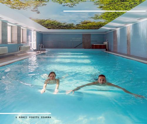 小莫拉夫卡Hotel Kamzík ***的男女在游泳池游泳