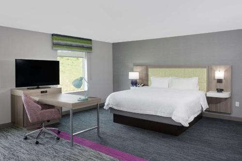 罗基希尔Hampton Inn & Suites Rocky Hill - Hartford South的一间卧室配有一张床、一张书桌和一台电视。