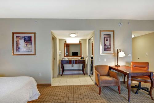皮奥里亚皮奥里亚大草原汉普顿套房酒店 的一间带一张床和一张书桌的卧室以及一间浴室。