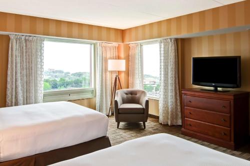 尼亚加拉瀑布希尔顿逸林瀑布景观Spa度假酒店-尼亚加拉大瀑布的酒店客房配有一张床、一台电视和一把椅子