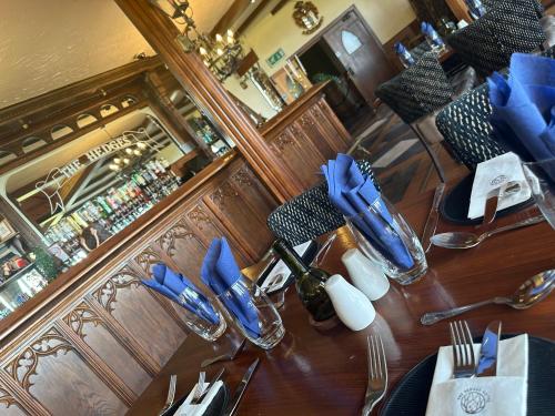 StranocumThe Hedges Hotel的餐厅的一张桌子,上面有蓝色的餐巾和餐具