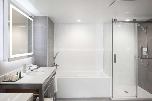 拉瓦尔希尔顿蒙特利尔/拉瓦尔酒店的带淋浴和盥洗盆的白色浴室
