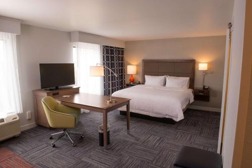 贝城Hampton Inn & Suites Bay City的酒店客房配有一张床、一张书桌和一台电视。