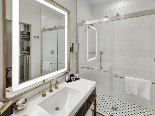塔尔萨Tulsa Club Hotel Curio Collection By Hilton的白色的浴室设有水槽和淋浴。