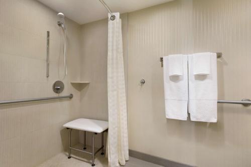 皮斯卡特维Embassy Suites by Hilton Piscataway Somerset的带淋浴、椅子和毛巾的浴室