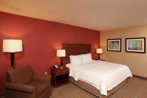 斯波坎Hampton Inn Spokane Airport的配有一张床和一把椅子的酒店客房