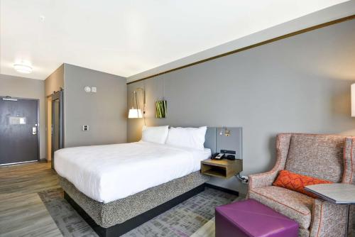 坦培亚利桑那州菲尼克斯/坦佩亚利桑那州立大学地区希尔顿花园酒店的配有一张床和一把椅子的酒店客房