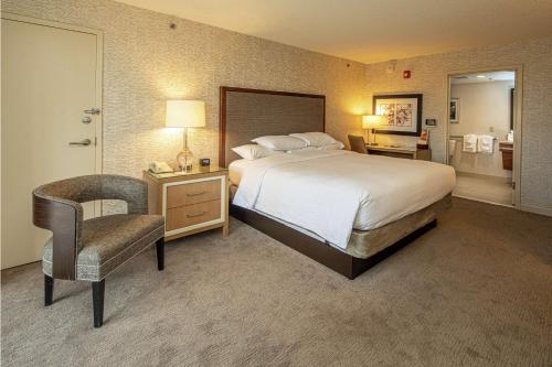 匹兹堡格林豪泰希尔顿逸林酒店绿树店的配有一张床和一把椅子的酒店客房