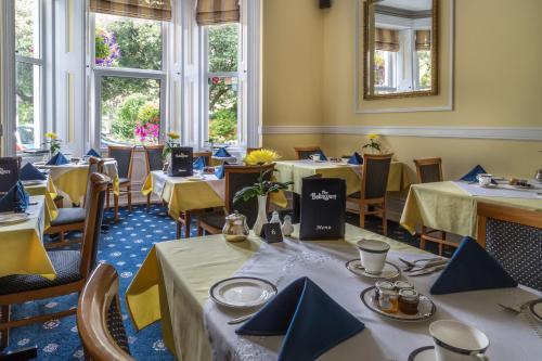 伯恩茅斯巴林科特酒店的一间配备有桌椅及蓝餐巾的用餐室