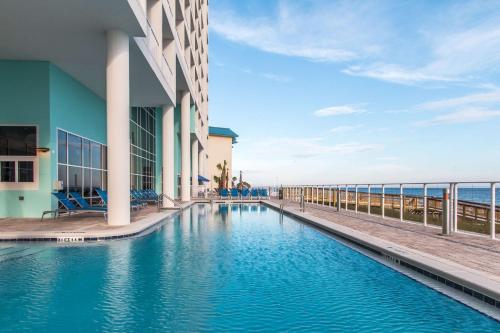 巴拿马城海滩Hampton Inn & Suites Panama City Beach-Beachfront的毗邻大海的建筑物的游泳池