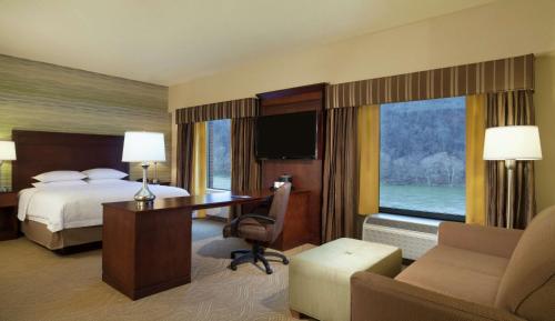 West HomesteadHampton Inn & Suites Pittsburgh Waterfront West Homestead的酒店客房带一张床、一张桌子、一张床和窗户。