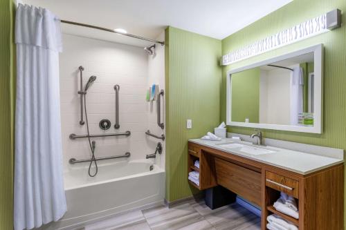 多佛尔多佛尔套房酒店的一间带水槽、浴缸和镜子的浴室