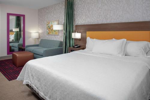 森特尼尔Home2 Suites By Hilton Denver South Centennial Airport的酒店客房带一张大床和一把椅子