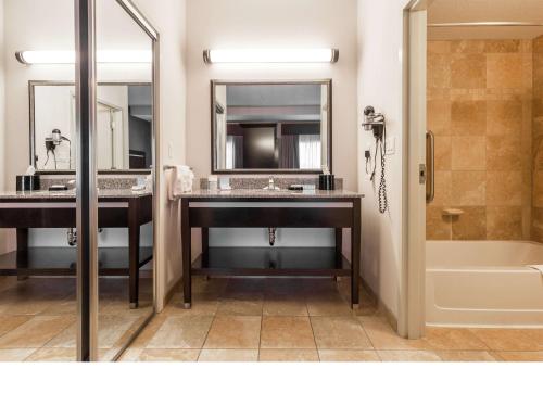 莱斯布里奇莱斯布里奇希尔顿恒庭酒店的浴室设有2个水槽、浴缸和镜子