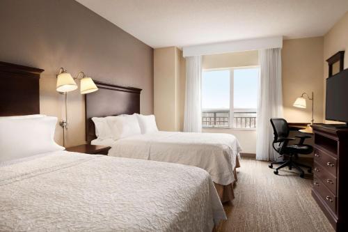 斯特灵汉普顿华盛顿杜勒斯国际机场酒店的酒店客房设有两张床、一张书桌和一个窗户。