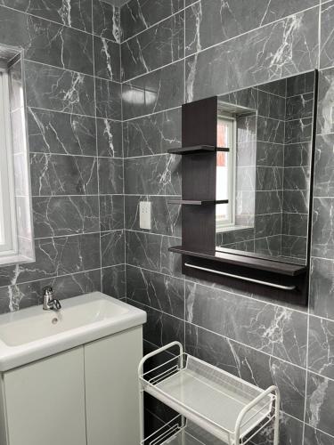 曼彻斯特Cozy house with free parking的黑色瓷砖浴室设有水槽和镜子