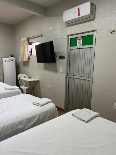 福塔莱萨Pousada da Celma的客房设有两张床和一扇带电视的门。