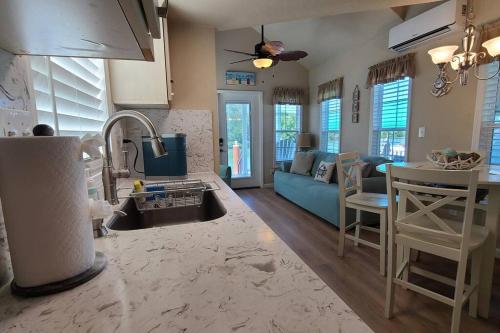 JewfishKokomo! - Tiny House with Boat Lift, Waterfront, Tiki的厨房以及带蓝色沙发的客厅。