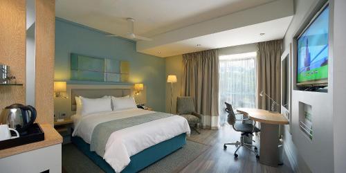 蓝海湾Holiday Inn Mauritius Mon Trésor, an IHG Hotel的配有一张床和一台平面电视的酒店客房