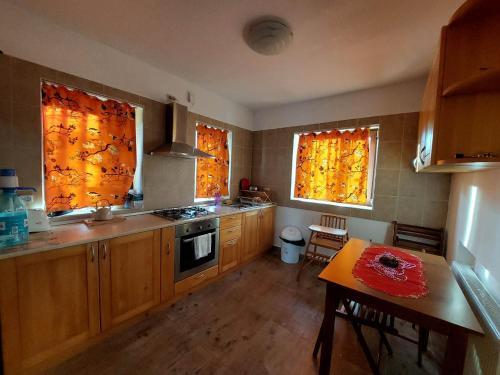 布雷亚扎Casa Vlazilor的厨房配有木制橱柜、2扇窗户和1张桌子