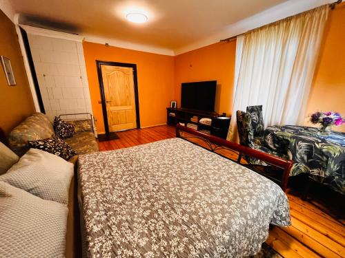 里加Unique Mailo cottage的一间卧室设有橙色的墙壁、一张床和电视