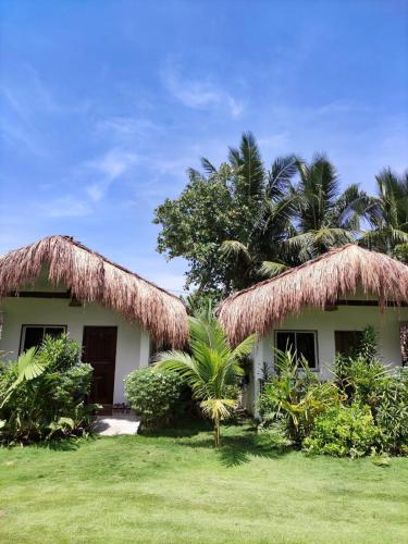 卢纳将军城Tropical Bungalows-Siargao的两顶茅草屋顶和棕榈树的房子