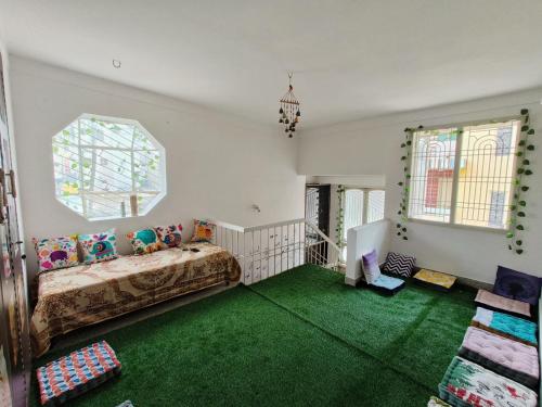 迈索尔Tusker Tribe的客房设有床、窗户和绿色地毯。