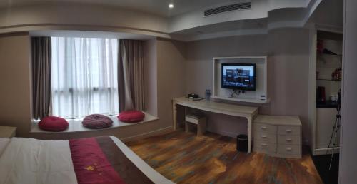 铜仁铜仁世纪大酒店的一间卧室配有书桌,窗户上配有电视。