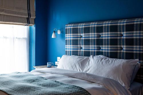 Nailsea贝克韦尔乔治宾馆的一间卧室拥有蓝色的墙壁,配有一张带白色枕头的床。