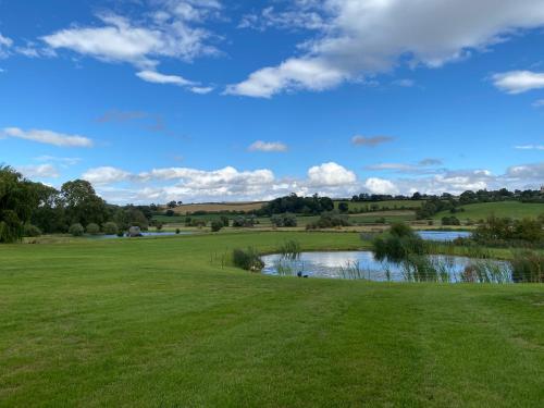 KettonThe Black Swan Shepherd Hut的享有高尔夫球场和绿色池塘的景色