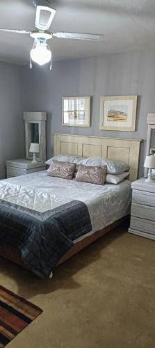 德班Wylie Hall Guesthouse的一间卧室配有一张大床、两张桌子和两盏灯。